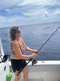 An angler actively reeling in a catch while fishing on a boat in open waters, showcasing a vibrant fishing environment.