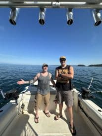 Two anglers enjoying a sunny day on a fishing boat, showcasing the interior setup with fishing rods ready for action.