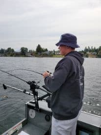 A young angler actively fishing from a boat, showcasing the excitement of the catch in a scenic lake environment.