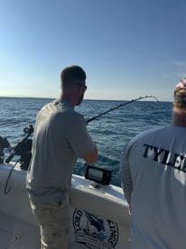 Angler actively reeling in a catch while fishing aboard a charter boat in open waters.