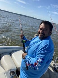 An angler actively fishing from a boat, enjoying a sunny day on the water.