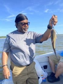 An angler proudly displaying a freshly caught fish while enjoying a day on the water, showcasing a relaxed fishing environment.