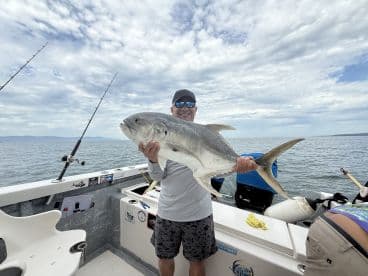 Angler proudly displaying a large Jack Crevalle on a fishing boat, showcasing a successful day on the water.