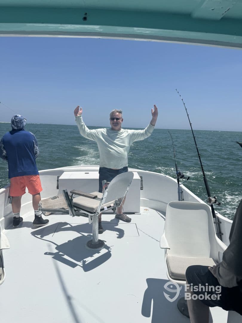 A group of anglers enjoying a day on the water, with one person playfully posing on the boat's deck.