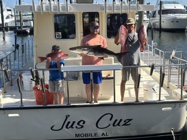 A family proudly displaying their catch of Red Snapper and a large Black Grouper aboard the 'Jus Cuz' charter in Mobile, AL.