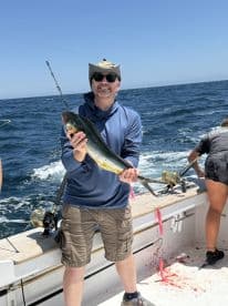 An angler proudly displaying a large Mahi Mahi while fishing on a charter boat in open waters.