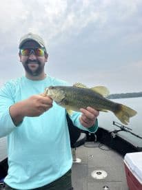 Angler proudly displaying a large Largemouth Bass while fishing on a boat, showcasing a successful day on the water.