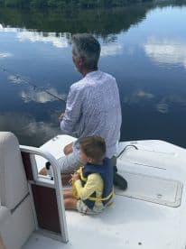 A grandparent and child enjoying a peaceful fishing experience on a calm river, showcasing a bonding moment in a scenic environment.