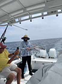 Angler displaying a sizable fish on a boat, capturing a memorable moment during a deep-sea fishing trip.