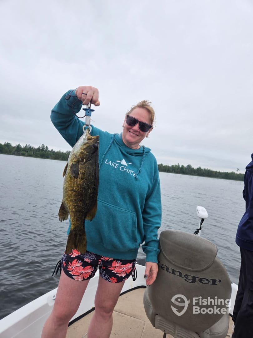 An angler proudly displaying a large Smallmouth Bass while fishing on a lake, showcasing a vibrant fishing environment.
