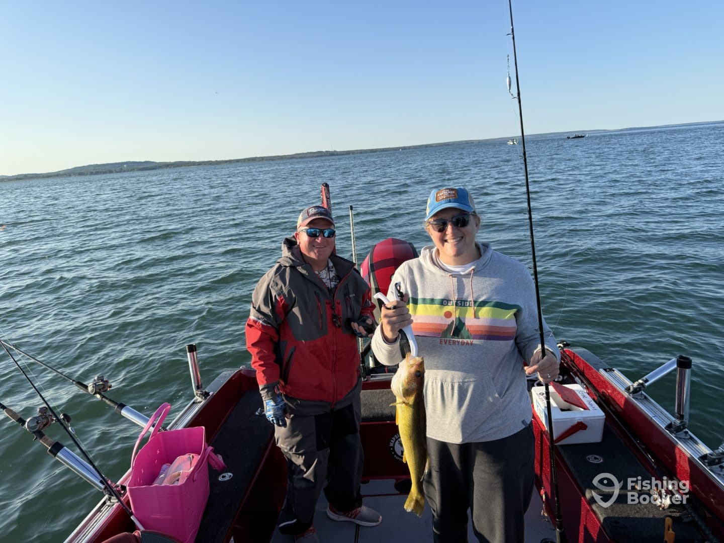 Two anglers on a fishing boat, with one proudly displaying a freshly caught Walleye. The serene lake setting enhances the fishing experience.