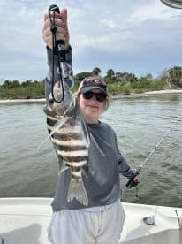 A young angler proudly displaying a striped fish while fishing from a boat in a scenic coastal environment.