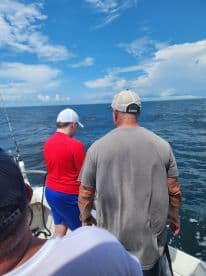 A young angler and an adult are engaged in fishing on a boat, enjoying a sunny day on the water.