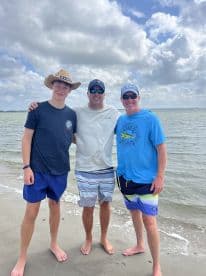 Three individuals enjoying a day at the beach, with a scenic coastal backdrop.