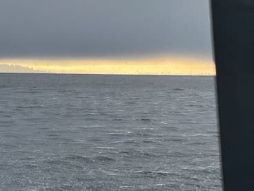 A scenic view of the ocean under a cloudy sky, with a distant shoreline barely visible.