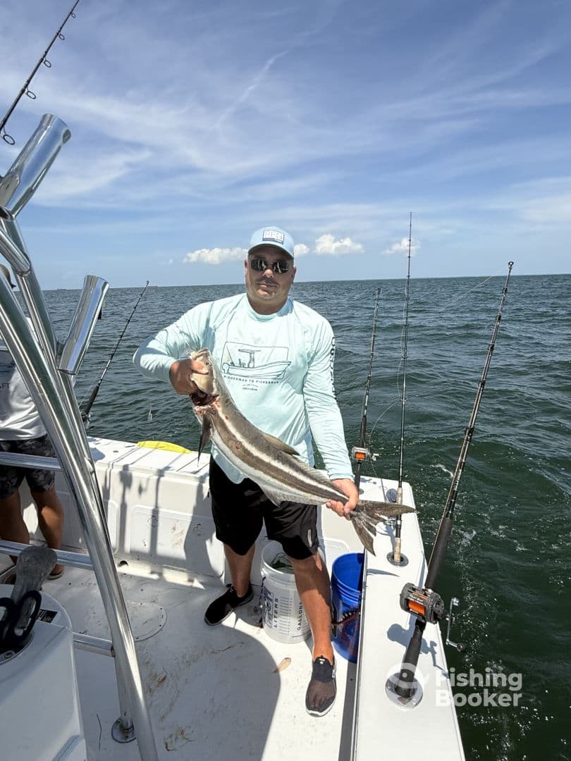 Angler proudly displaying a large striped fish aboard a fishing boat in open waters.