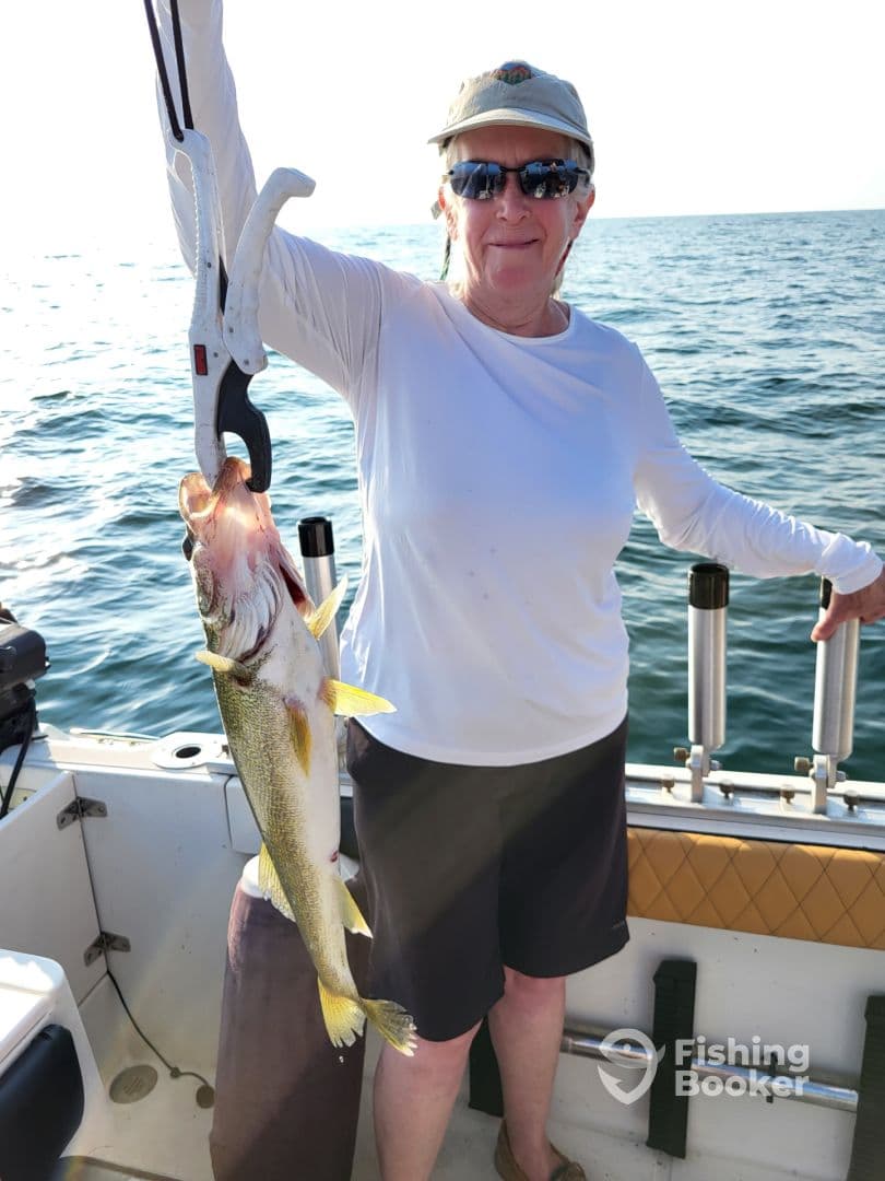 An angler proudly displaying a large Walleye while fishing on a boat, showcasing a successful catch in a sunny environment.