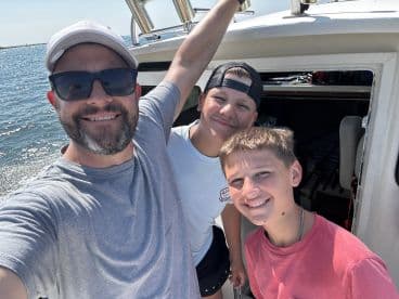 A joyful family moment aboard a fishing boat, showcasing two young anglers and an adult enjoying their time on the water.