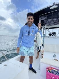 A proud angler holding a large fish on a boat, showcasing a successful fishing trip in open waters.