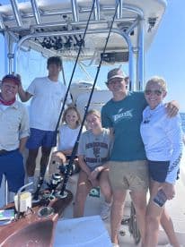 A group of young anglers and their guide enjoying a day on a fishing boat, showcasing the interior setup with fishing rods ready for action.