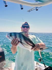 Angler proudly displaying a large Mahi Mahi while fishing offshore, showcasing a sunny day on the water.