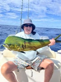An angler proudly displaying a vibrant Mahi Mahi while fishing offshore, showcasing the beautiful blue ocean backdrop.