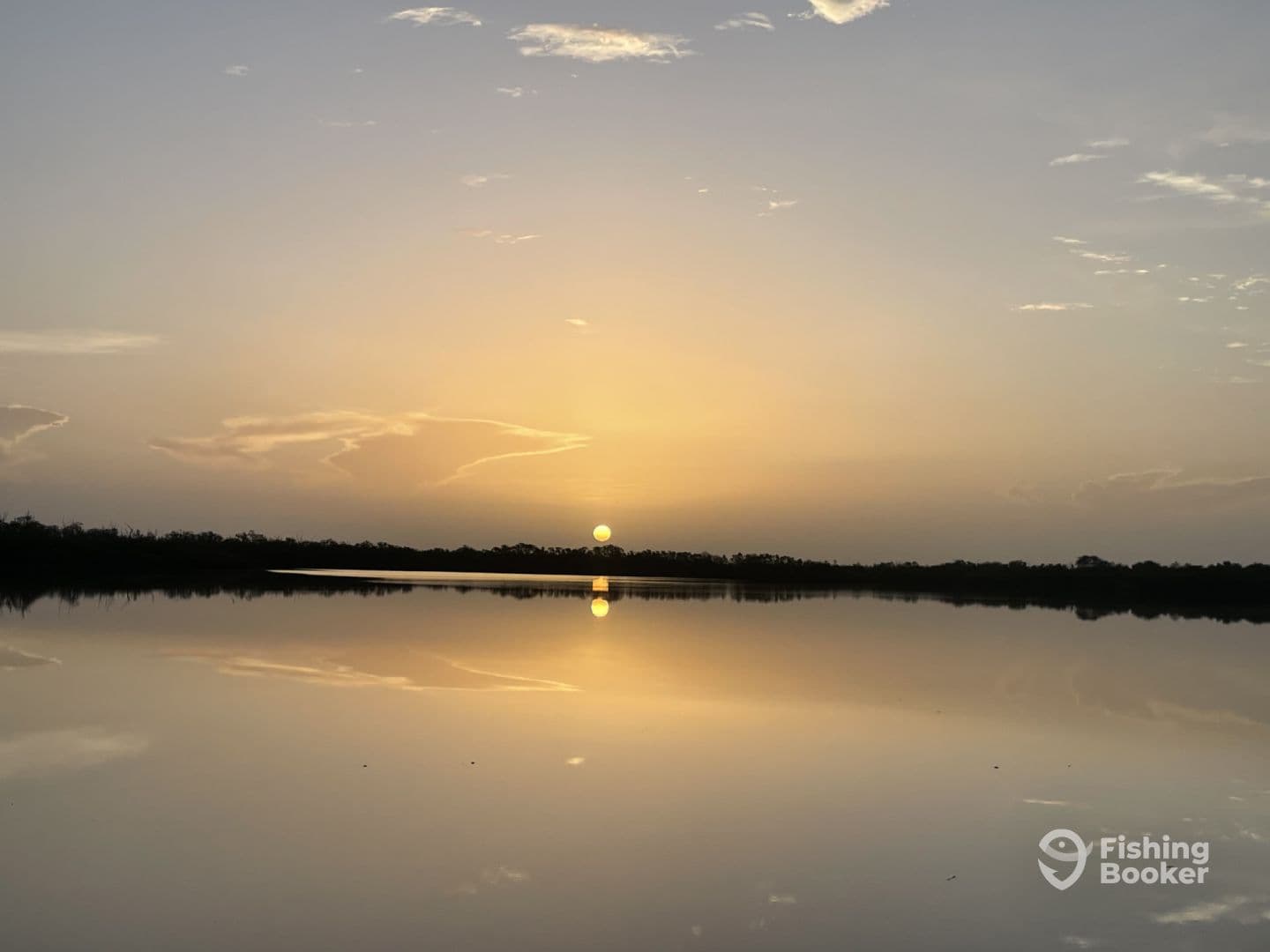 A serene sunset over calm waters, reflecting the vibrant colors of the sky, creating a tranquil fishing environment.