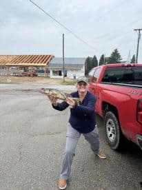 An enthusiastic angler proudly displaying a Walleye caught near a construction site, showcasing the excitement of fishing in a local area.