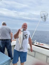 An angler proudly displaying a freshly caught fish while on a fishing charter in open waters.