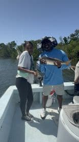 A young angler and an adult proudly displaying a caught fish while enjoying a day on the water in a scenic fishing environment.