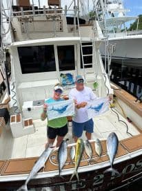 Two anglers proudly displaying their catch of Mahi Mahi and Kingfish on the boat after a successful fishing trip in Florida.