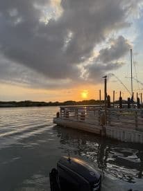 A scenic view of a dock at sunset, showcasing the peaceful fishing environment with boats moored nearby.