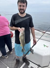 An angler proudly displaying a freshly caught Walleye while fishing on a boat, showcasing a successful day on the water.