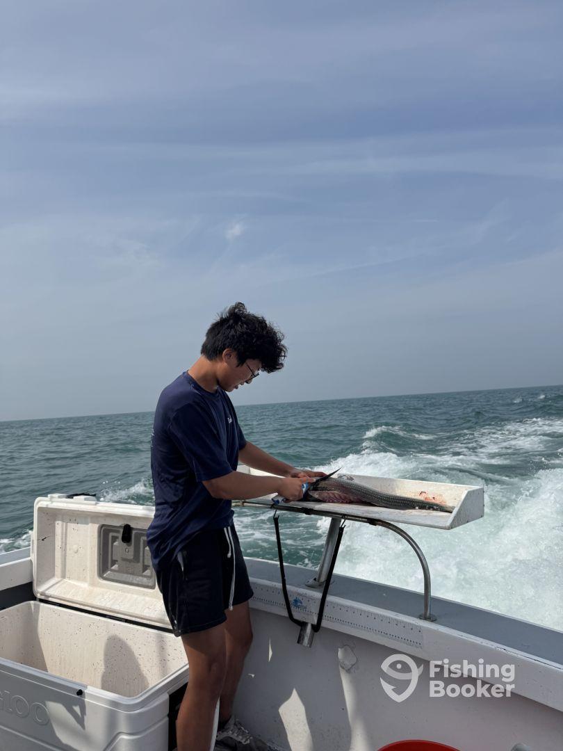 A young angler filleting a fish on a boat while enjoying a day out on the water.