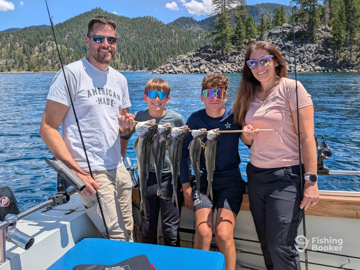 A family proudly displaying their catch of several Lake Tahoe trout while enjoying a sunny day on the water.