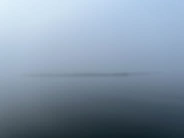 A foggy scene on the water, lacking clear visibility of any subjects or features.