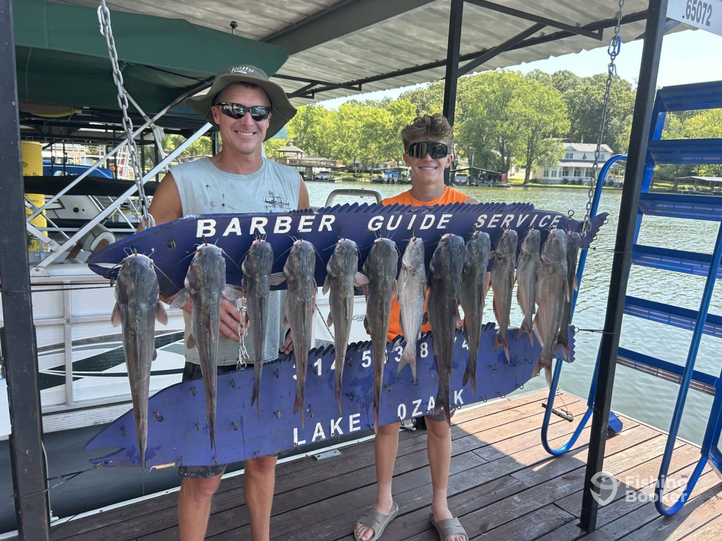 Two anglers proudly displaying a catch of catfish on a board at Lake Ozark, showcasing a successful fishing trip.