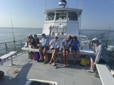 A lively group of anglers enjoying their time on a fishing charter boat, showcasing a relaxed atmosphere on the water.