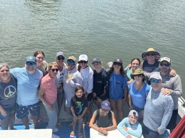 A large group of anglers posing together on a boat, enjoying a day of fishing on the water.