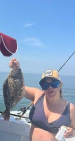 Angler proudly displaying a Flounder while fishing on a sunny day at sea.