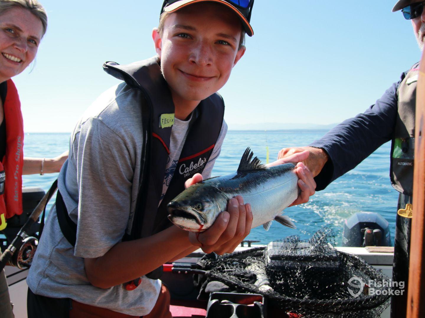 A young angler proudly displaying a caught fish while enjoying a day on the water, surrounded by fellow fishing enthusiasts.