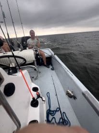 A young angler enthusiastically reeling in a fish while fishing on a boat, showcasing a lively fishing experience on the water.