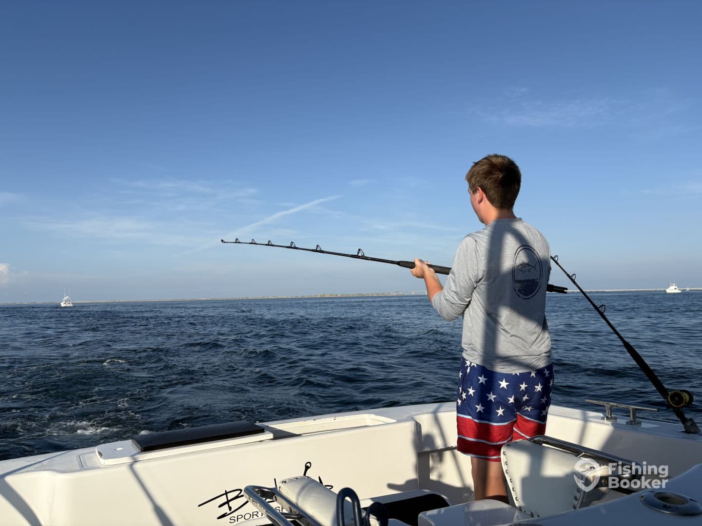 A young angler is actively reeling in a catch while fishing on a sport fishing boat, showcasing the excitement of the fishing experience.