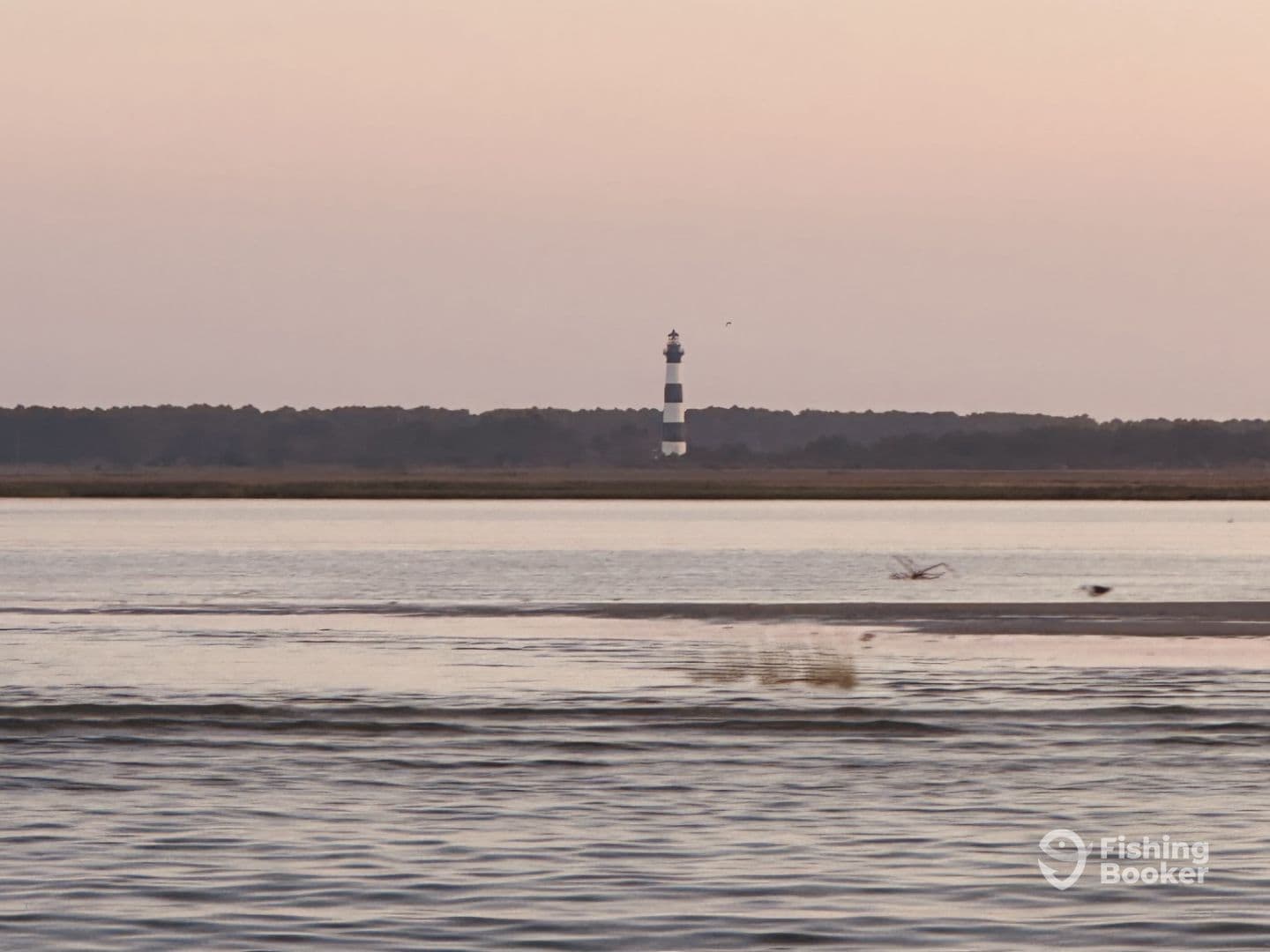 A distant view of a lighthouse at dusk, surrounded by calm waters and a serene landscape.
