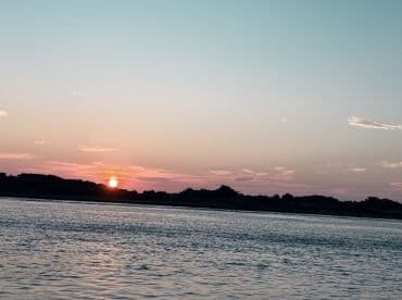 A serene sunset over calm waters, capturing the tranquil beauty of a fishing environment.