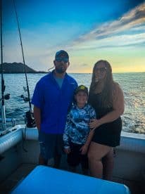 A family poses together on a fishing boat during sunset, showcasing a relaxed atmosphere on the water.