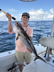 A young angler proudly displaying a large Cobia while fishing offshore, showcasing a successful day on the water.