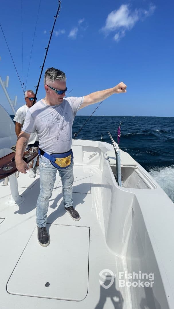 Angler actively reeling in a fish while fishing on a boat in open waters, showcasing a vibrant fishing environment.