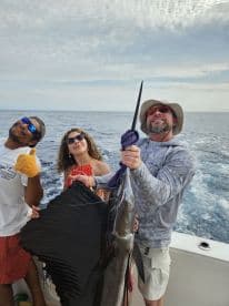 Group of anglers celebrating a successful catch of a large Sailfish while out on the open ocean.