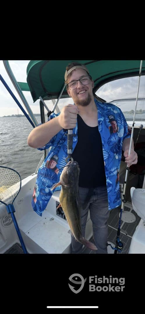 An angler proudly displaying a large catfish while fishing on a boat, showcasing a fun day on the water.